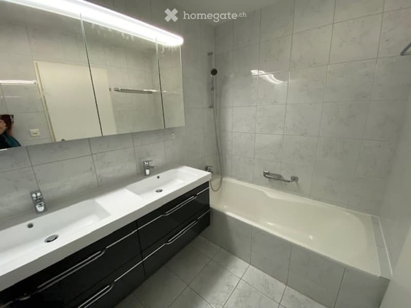 Modern bathroom with two sinks, a bathtub, and a large mirror above the sinks.