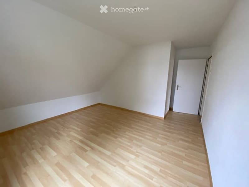 Empty room with wooden flooring and white walls, featuring a single white door.
