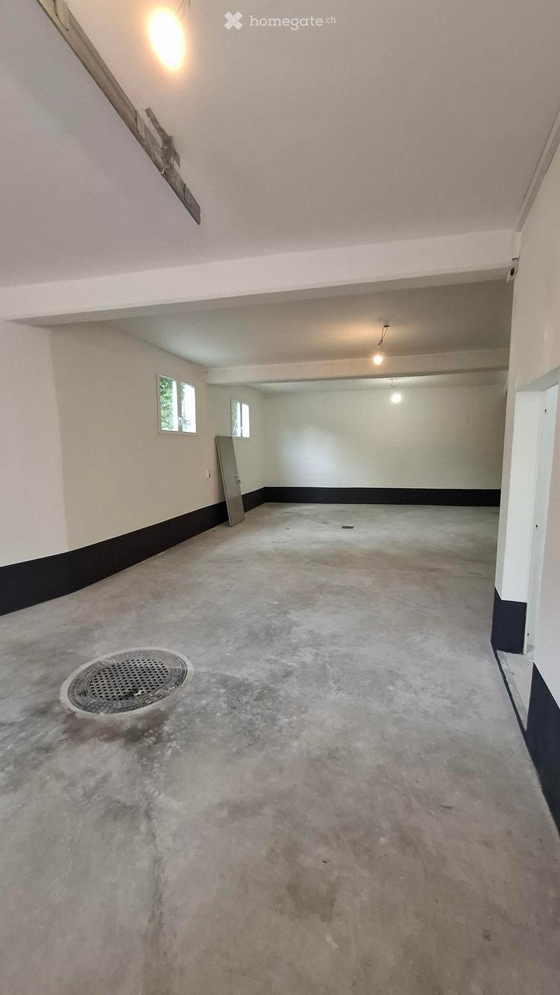 Empty room with concrete floor, white walls, small windows, and a metal door. No furniture or equipment present.