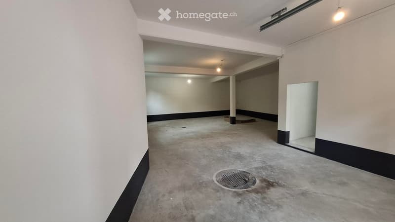 Empty room with concrete floor, white walls, and a drain cover in the center. No furniture or equipment present.