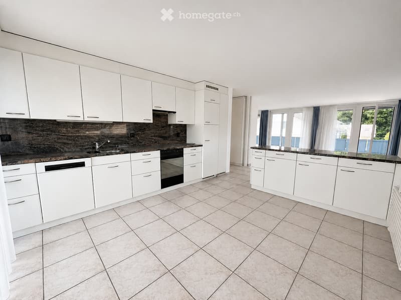 Modern kitchen with white cabinets, tiled floor, and stainless steel appliances including a sink, oven, and dishwasher.