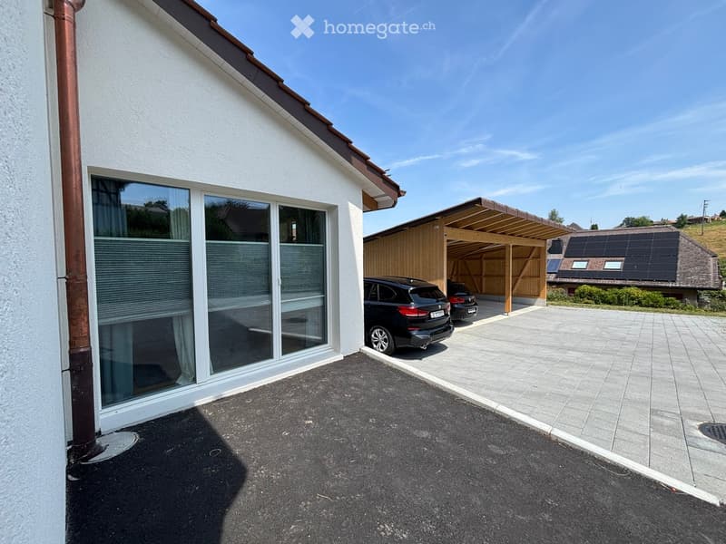 Modern house exterior with large windows, garage, and solar panels on neighboring roof.
