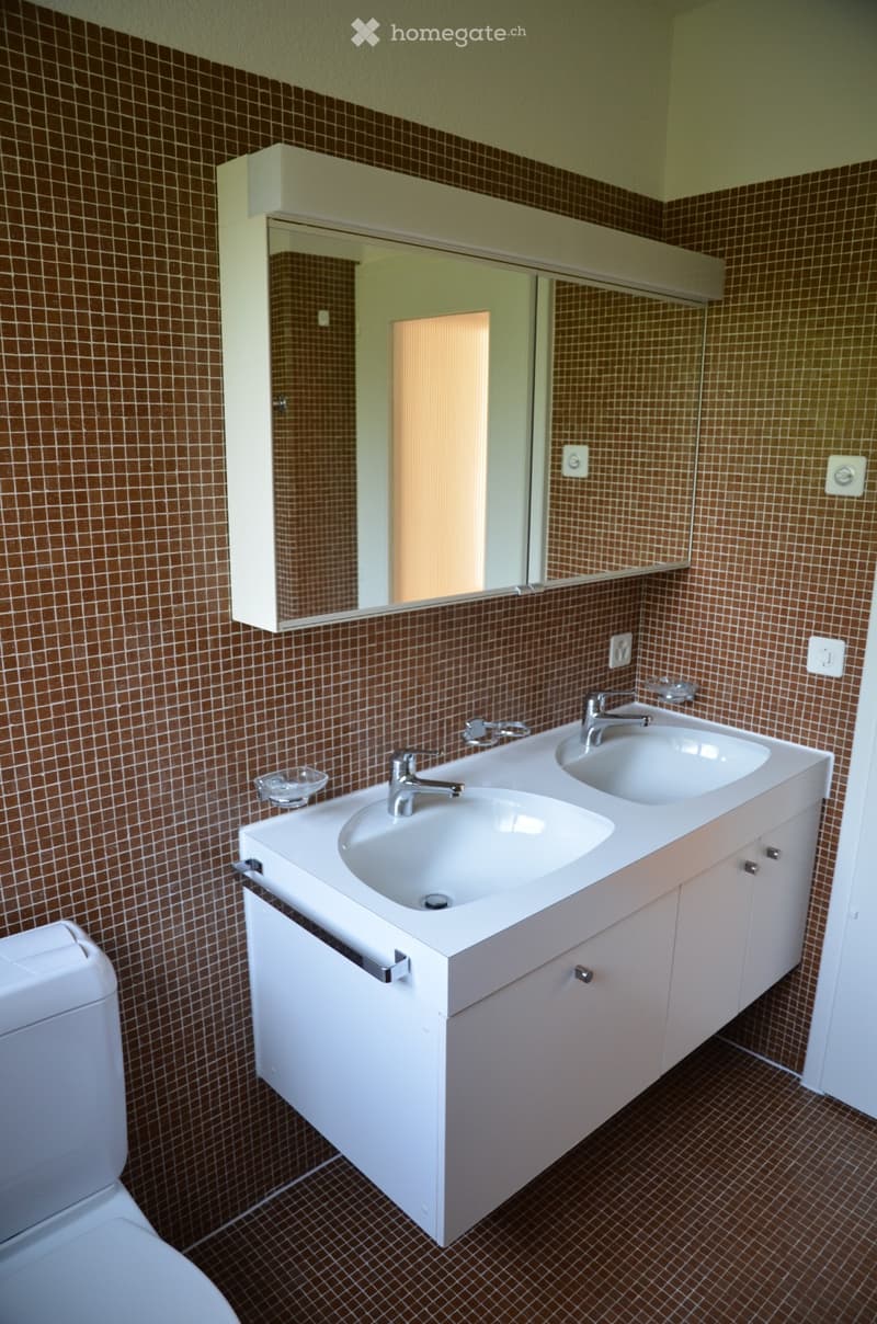 Bathroom with double sink, mirror, and toilet