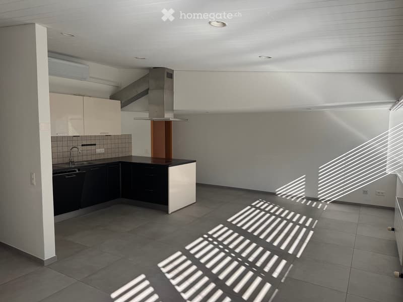 Modern kitchen with white cabinets, black countertops, and stainless steel appliances, including a sink, faucet, and dishwasher. Sunlight streams in, casting shadows on the tiled floor.