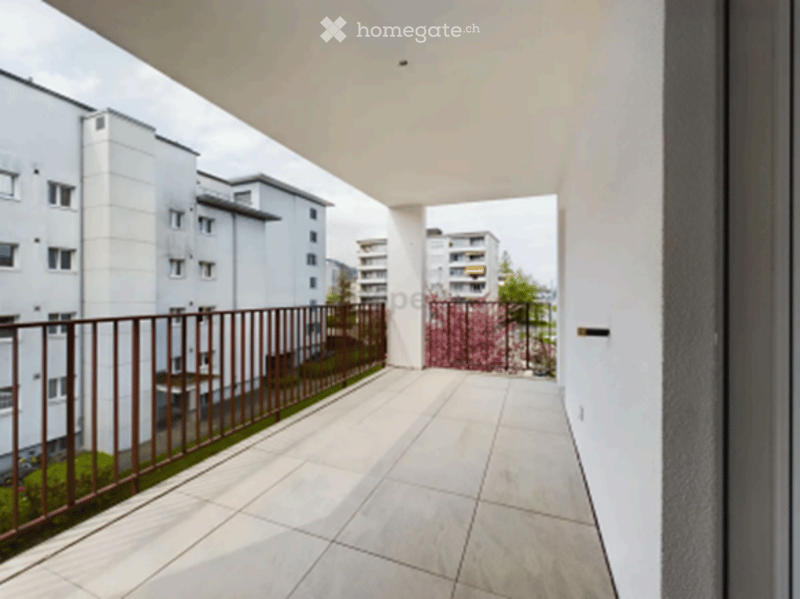 Modern balcony with tiled flooring, metal railing, and a view of neighboring buildings and greenery.