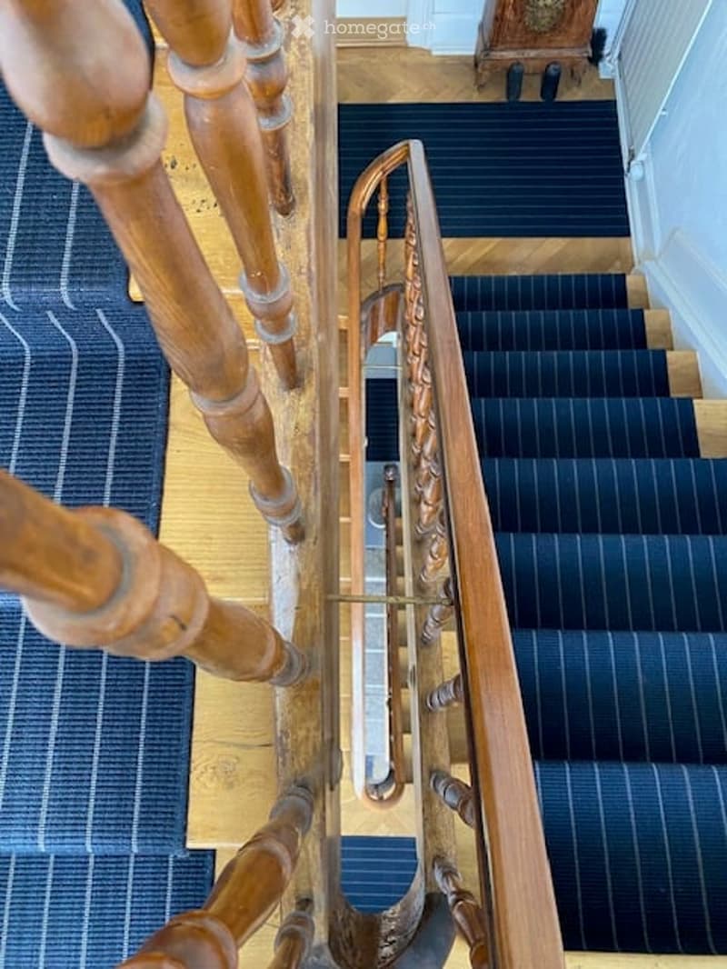 wooden staircase, blue carpet, brown handrail