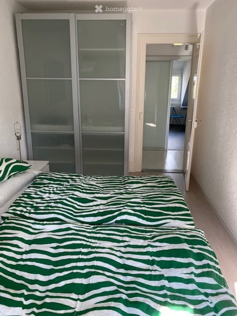 double bed, zebra pattern duvet, sliding glass wardrobe, lamp, white nightstand, doors open to balcony
