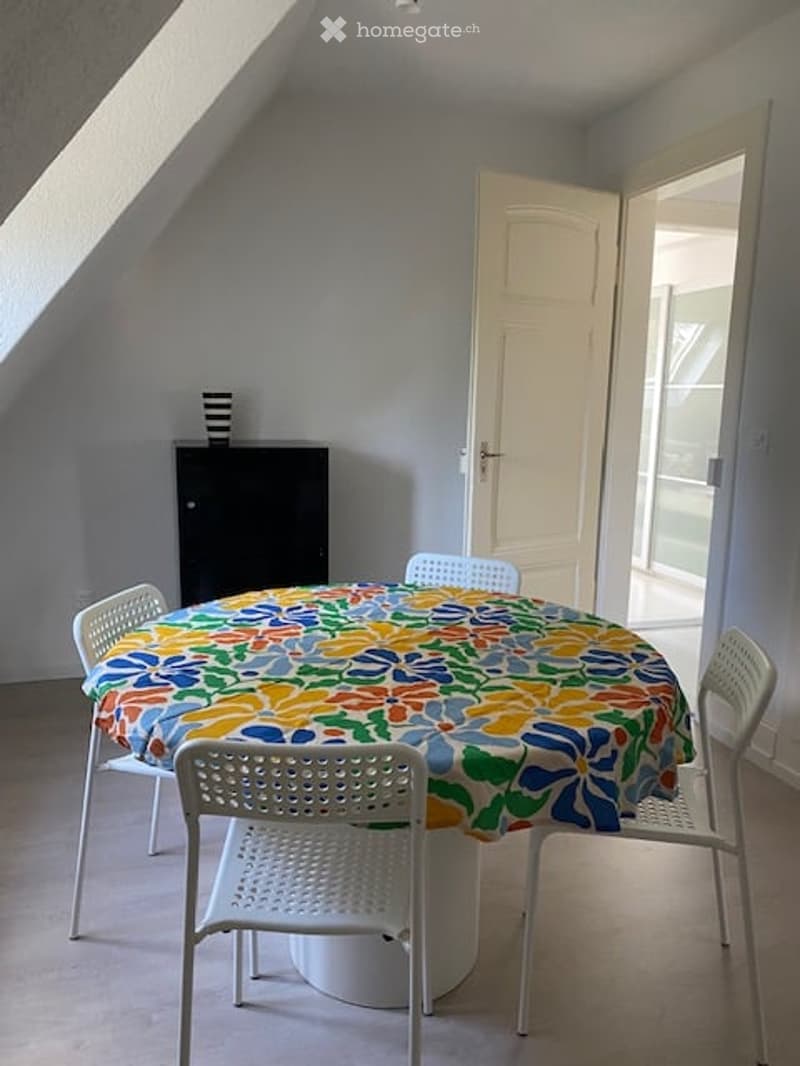 Dining room: circular dining table, floral tablecloth, 4 white chairs, white cabinet, door, window
