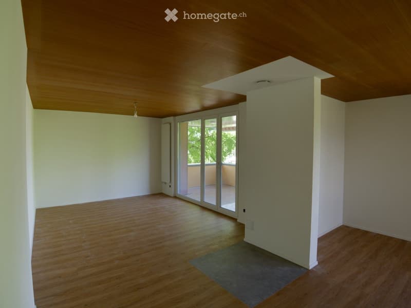 Empty room with wooden flooring, white walls, and a large sliding glass door leading to a balcony.