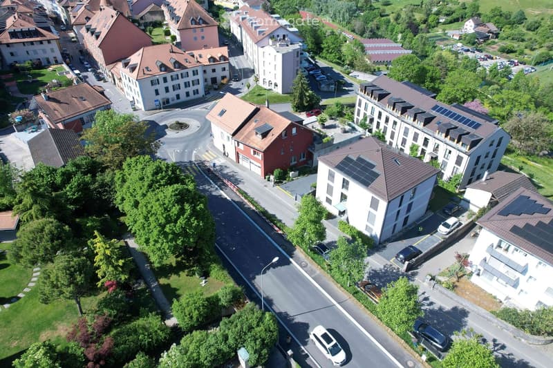Aerial view of a residential area with multiple buildings, parking lots, and greenery.