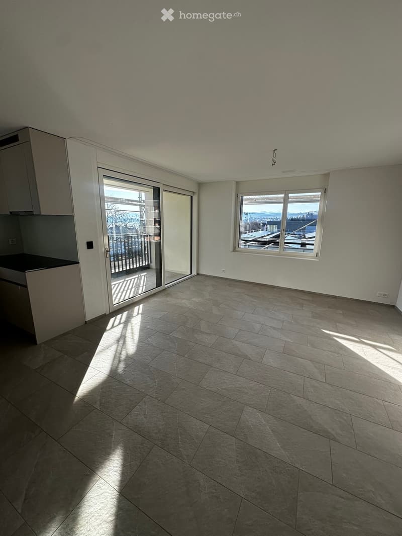 Empty room with tiled floor, large window, and sliding glass door leading to a balcony.