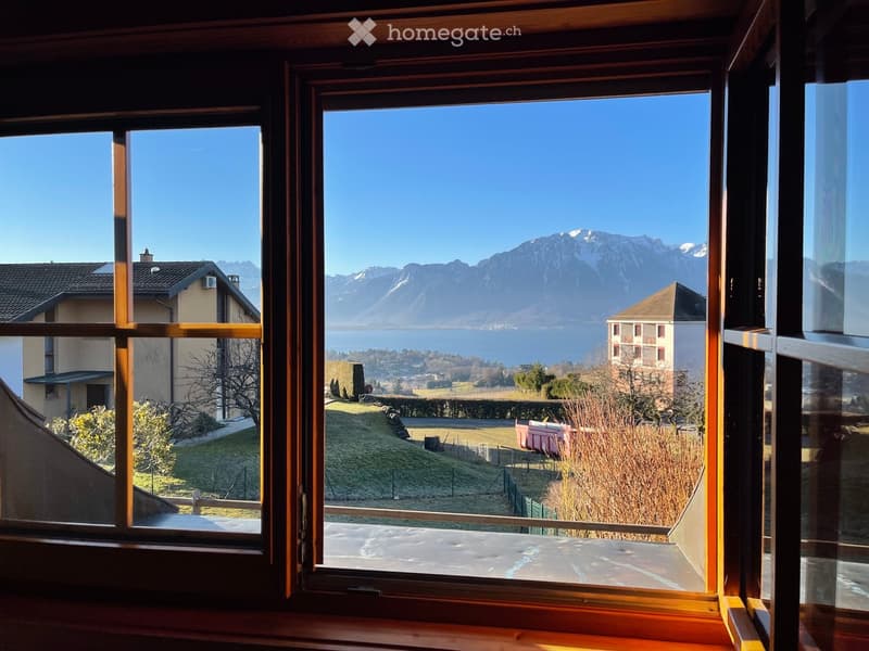 Other. View from a window showcasing a scenic landscape with mountains, a lake, and surrounding houses.