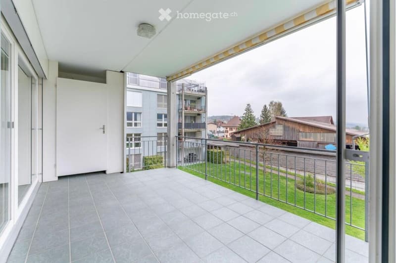 Balcony with tiled floor, metal railing, and a view of a residential area with buildings and greenery.