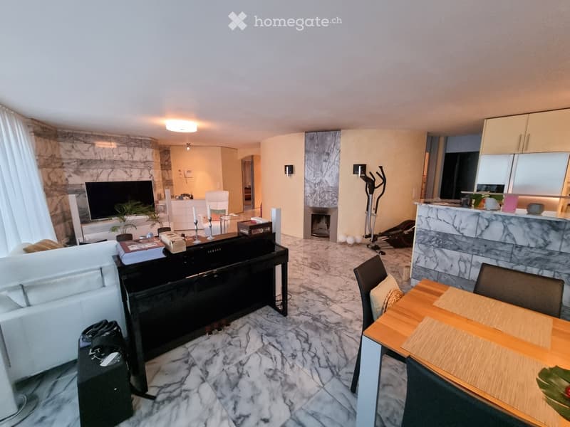 Modern open-plan living and dining area with a white sofa, coffee table, TV, dining table, chairs, fireplace, and kitchen island.