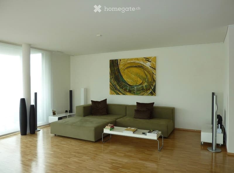 modern living room, wooden floor, white walls, beige couch with cushions, coffee table, picture on wall, speakers, bookshelves