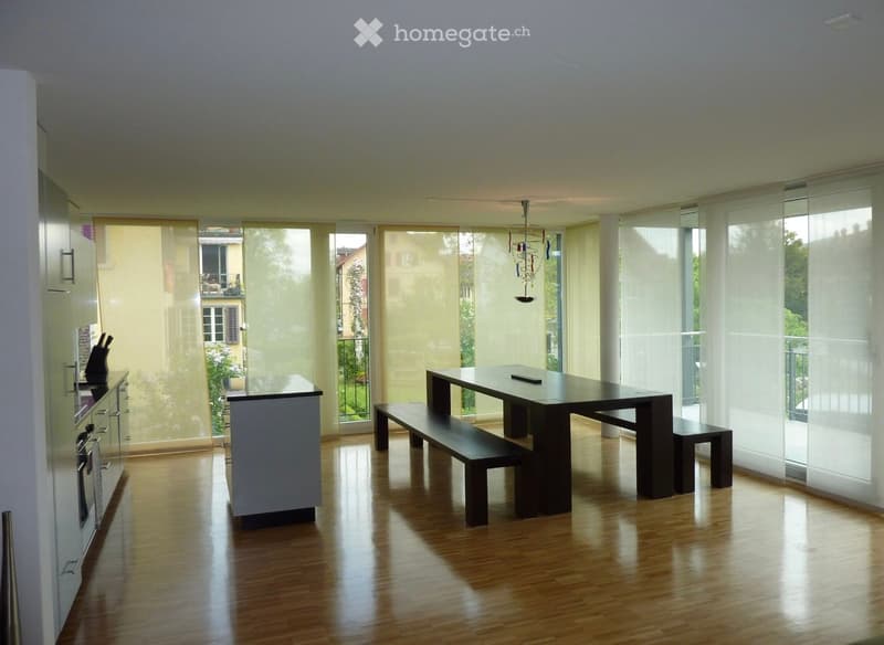 white walls, wooden floors, dining table, bench, window with curtain, kitchen area with appliances