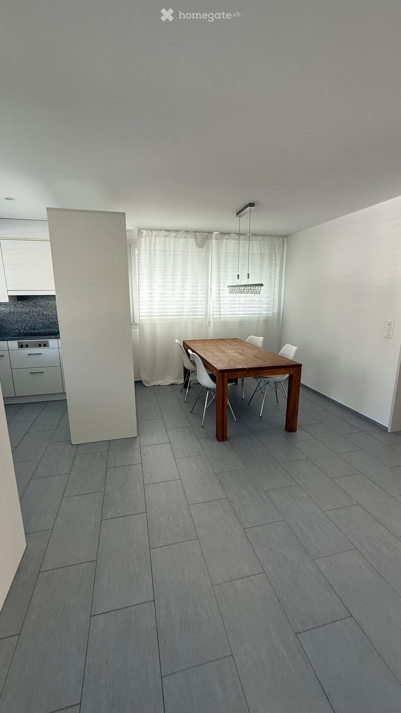 Dining room with a wooden table, four white chairs, white cabinets, and a window with white curtains.