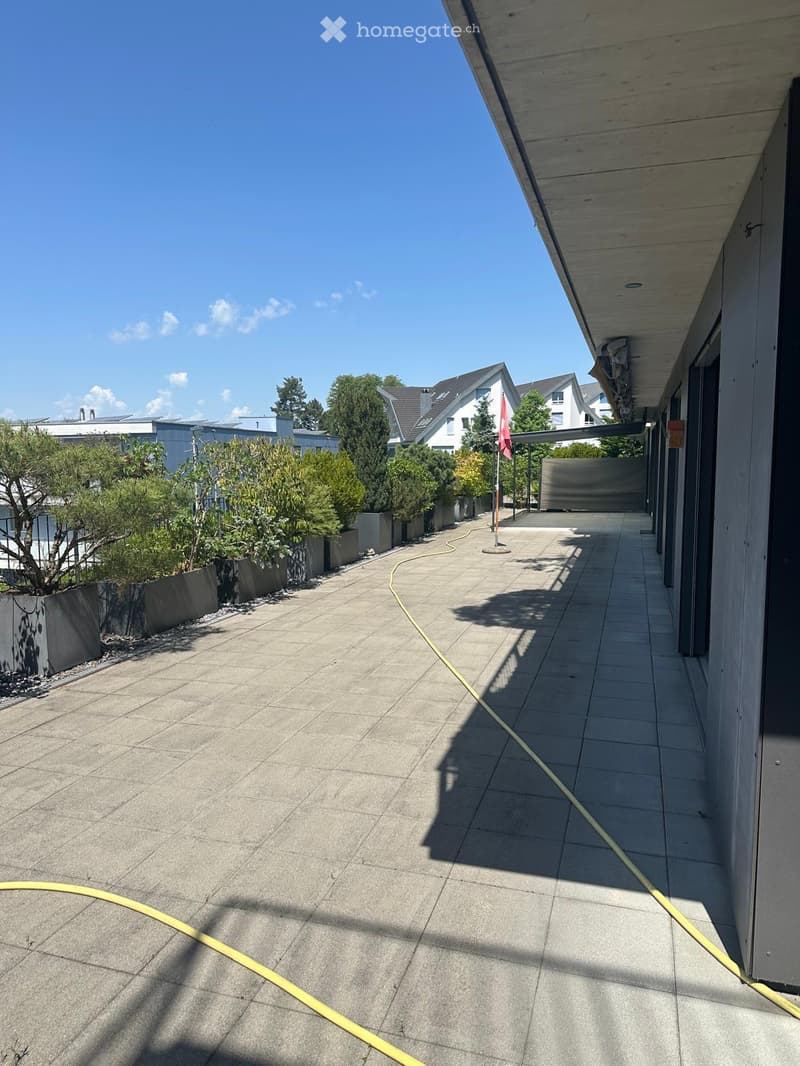 Balcony with tiled floor, modern design, and a view of neighboring houses and greenery.