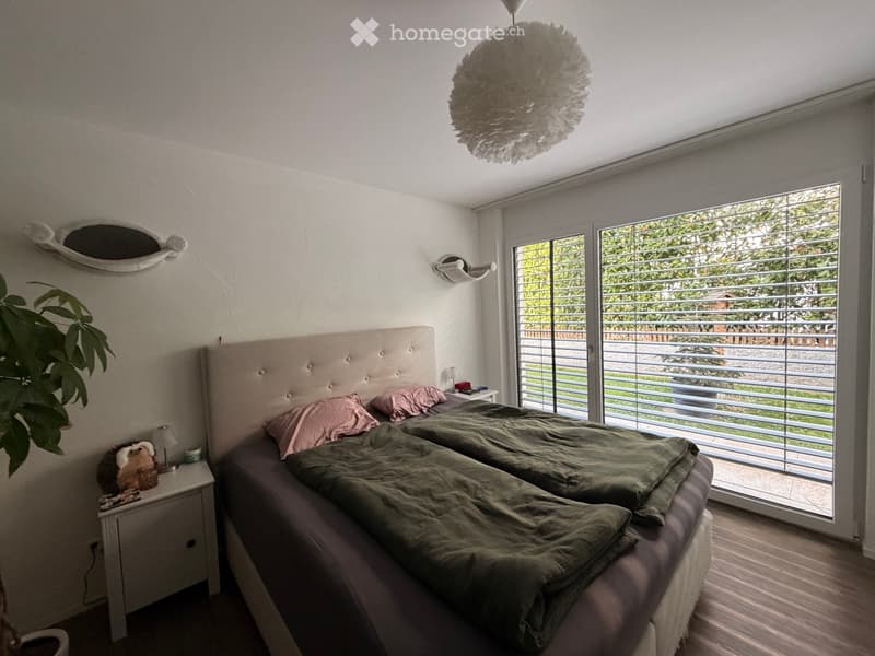 Modern bedroom with a large double bed, nightstands, a decorative mirror, and a hanging spherical light fixture.