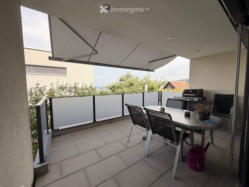 Balcony with tiled floor, table and chairs, grill, potted plant, and watering can.