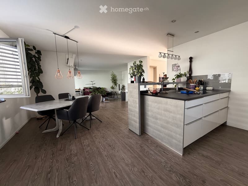 Modern kitchen and dining area with a white kitchen island, pendant lights, a dining table with chairs, and various decorative items.