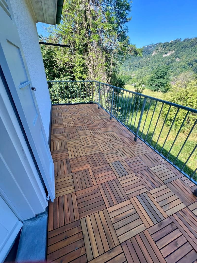 Wooden deck with herringbone pattern, metal railing, and scenic mountain view.