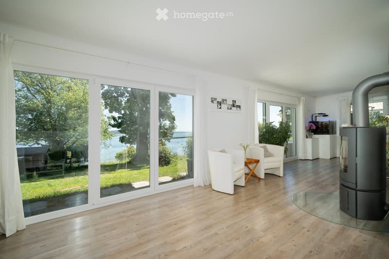 wooden floor, sliding glass doors, white chairs, fireplace, table with flower vase, aquarium