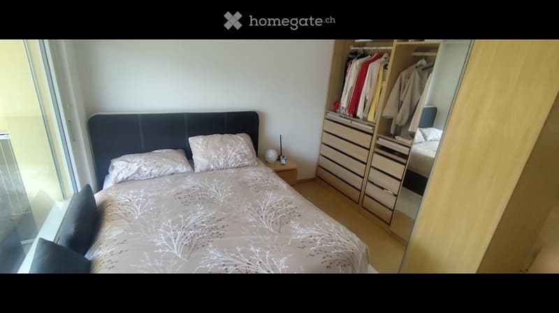 Modern bedroom with a large bed, nightstand, mirror, and built-in wardrobe with drawers.