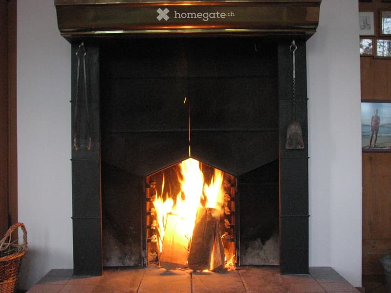 A black stone fireplace with a burning fire, surrounded by a wooden mantel and decorative elements.