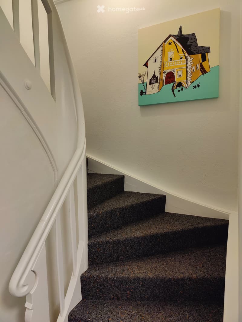 Carpeted staircase with white handrail and a colorful painting of a house on the wall.