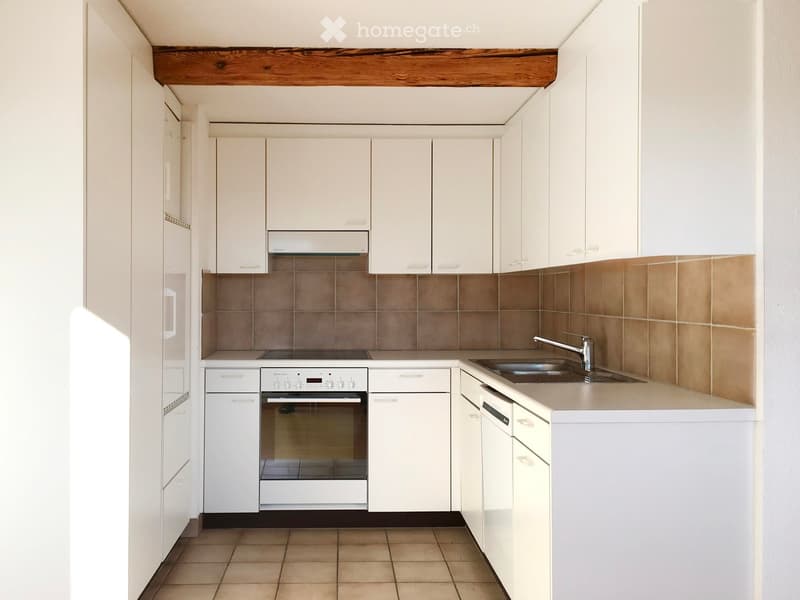 Modern kitchen with white cabinets, stainless steel sink, oven, and tiled backsplash.