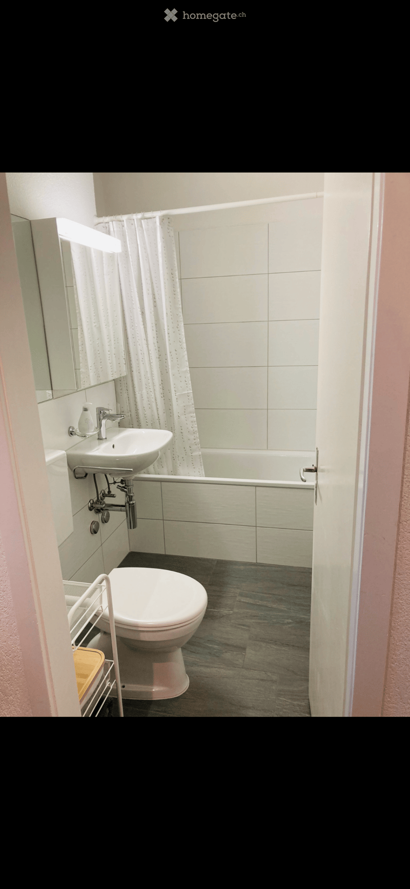 Bathroom with white tiles, bathtub, sink, toilet, mirror, and shower curtain
