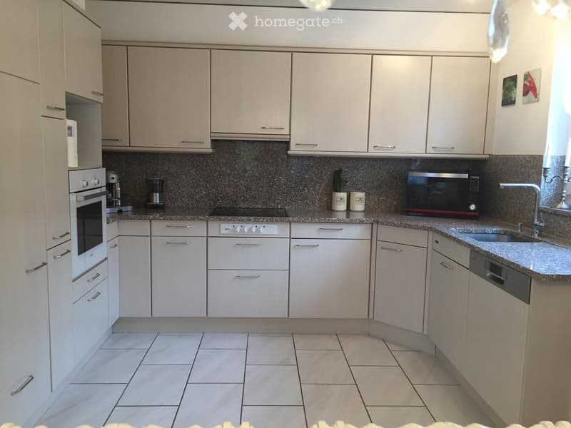 Modern kitchen with white cabinets, granite countertops, and stainless steel appliances including an oven, microwave, and sink.
