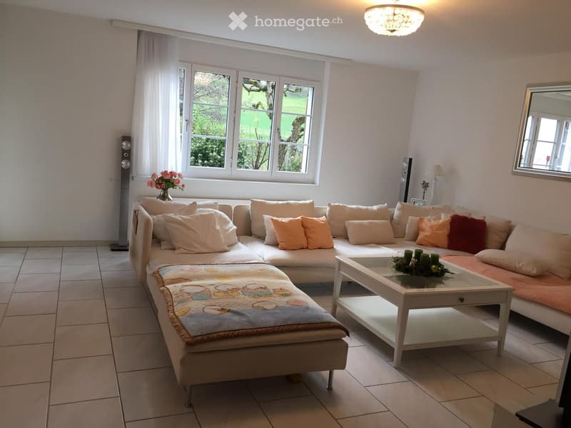 Living room with a large sectional sofa, throw, coffee table, vase, table runner, table centerpiece, table lamp, mirror, and speaker.