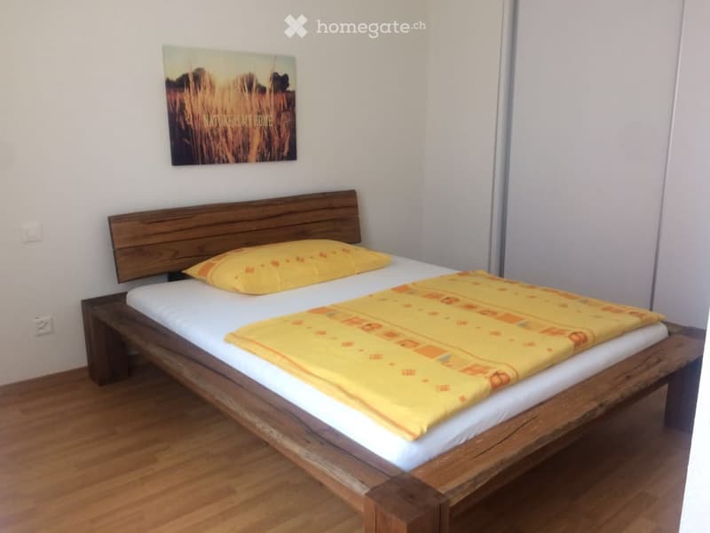A cozy bedroom with a wooden bed, yellow bedding, and a picture frame on the wall.