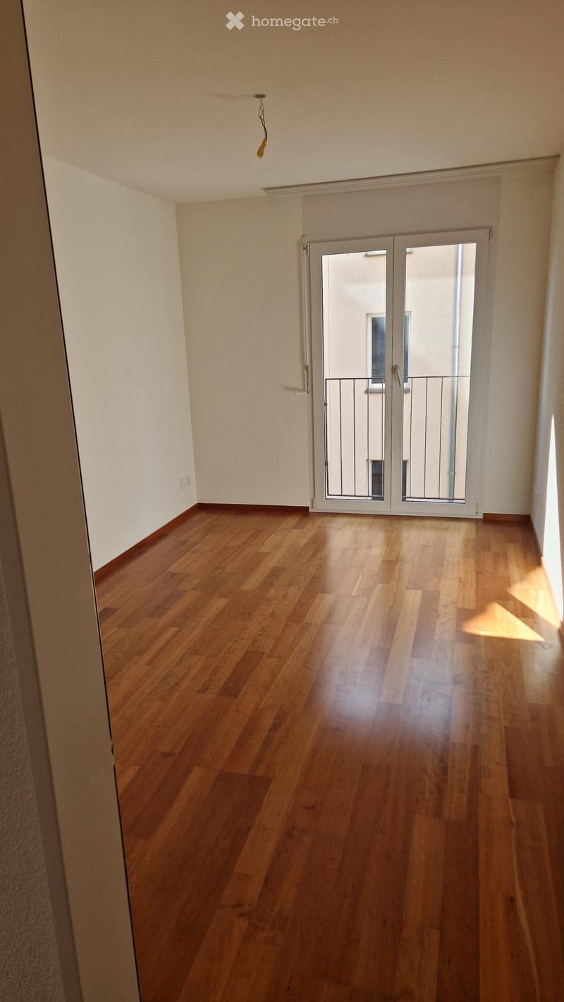 Empty room with wooden wall paneling and a large window with blinds. No furniture or equipment visible.