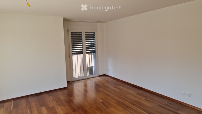 Empty room with white walls, wooden ceiling, and a large window with blinds.