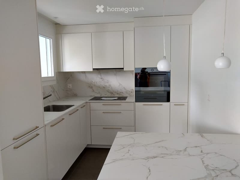 Modern kitchen with white cabinets, marble countertops, and stainless steel appliances.