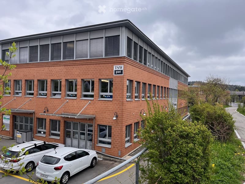 Two-story brick building with multiple windows and signage reading "TSW pat" and "Physio".