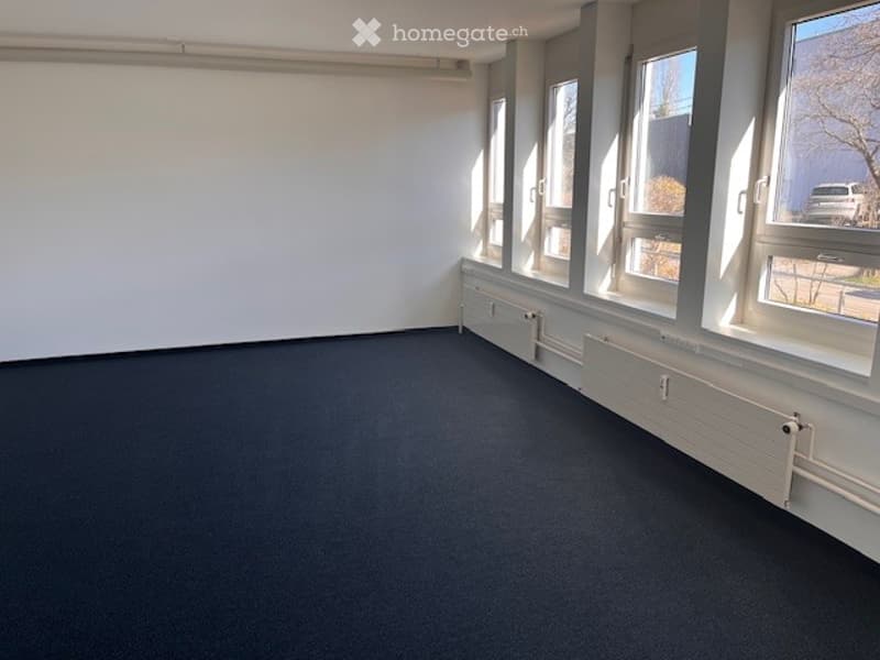 Completely empty room with bare walls and dark carpeted floor. No furniture or equipment.