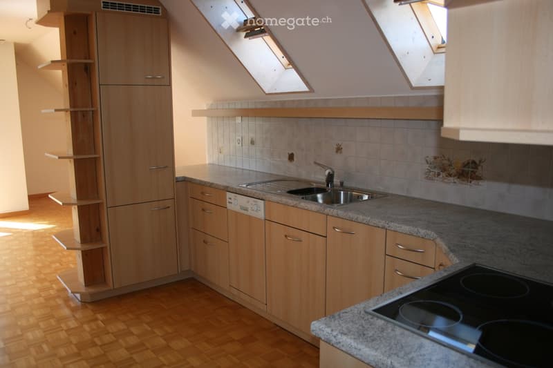 Modern kitchen with light wooden cabinets, granite countertops, stainless steel sink, electric stove, and built-in dishwasher. Skylight windows provide natural light.