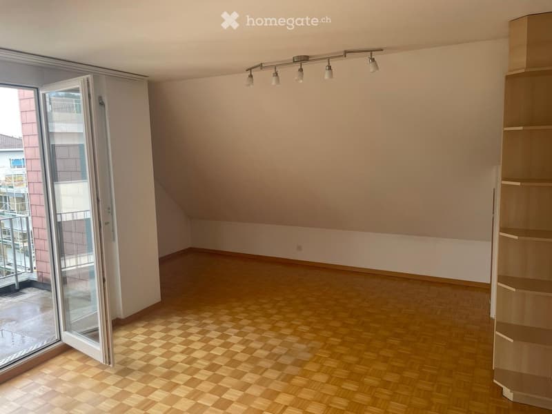 Empty room with wooden flooring, white walls, and a large sliding glass door leading to a balcony.