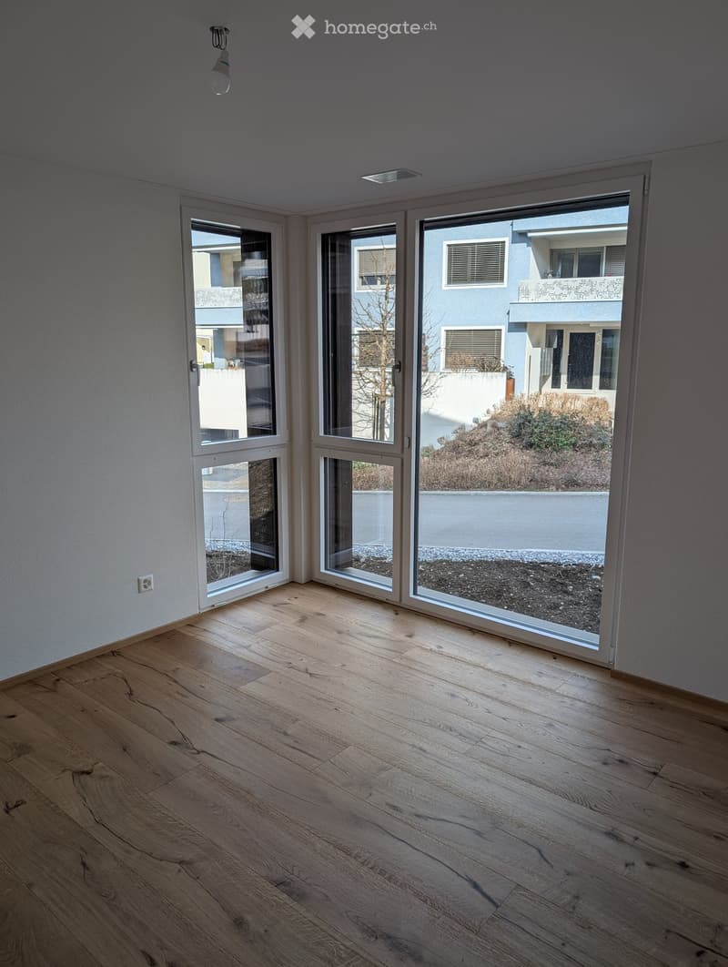 Empty room with light wooden flooring and large glass sliding doors leading to an outdoor area.