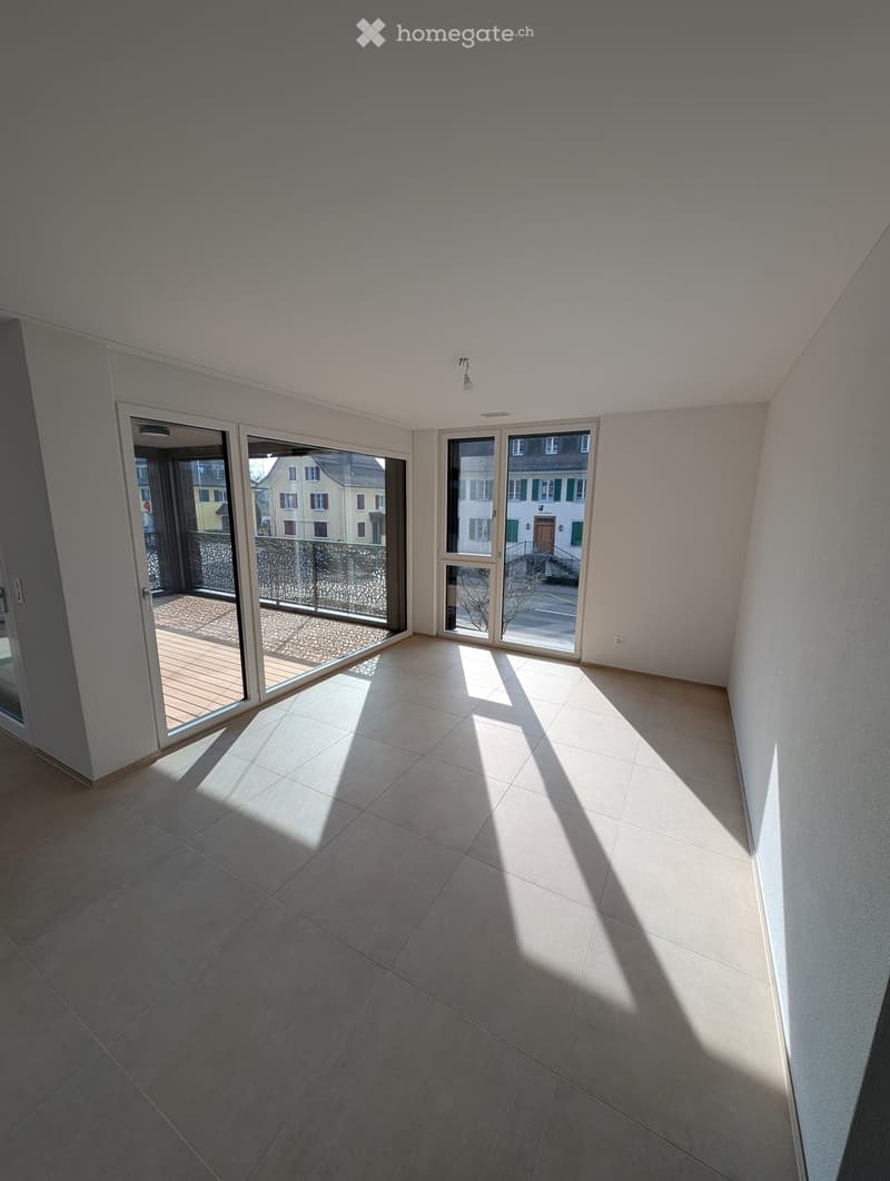 Empty room with tiled floor, large windows, and sliding glass doors leading to a balcony.
