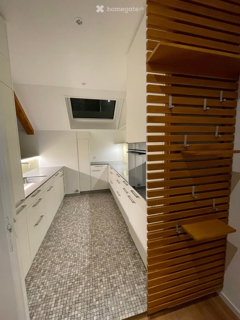 modern kitchen with white cabinets, tiled floor, wooden wall, sink, oven, skylight