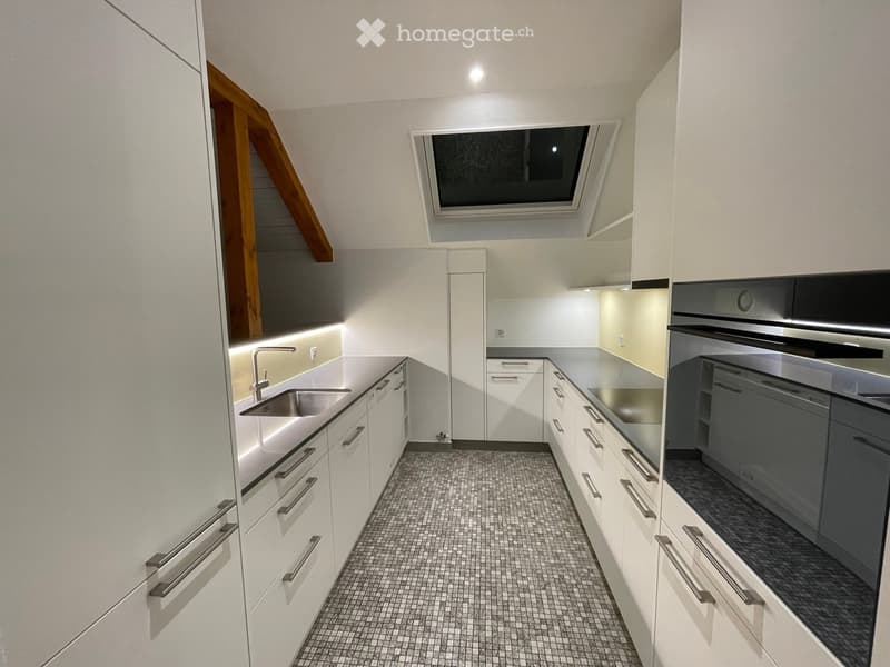 modern kitchen with white cabinets, stainless steel sink, tiled floor, built-in oven and dishwasher, skylight