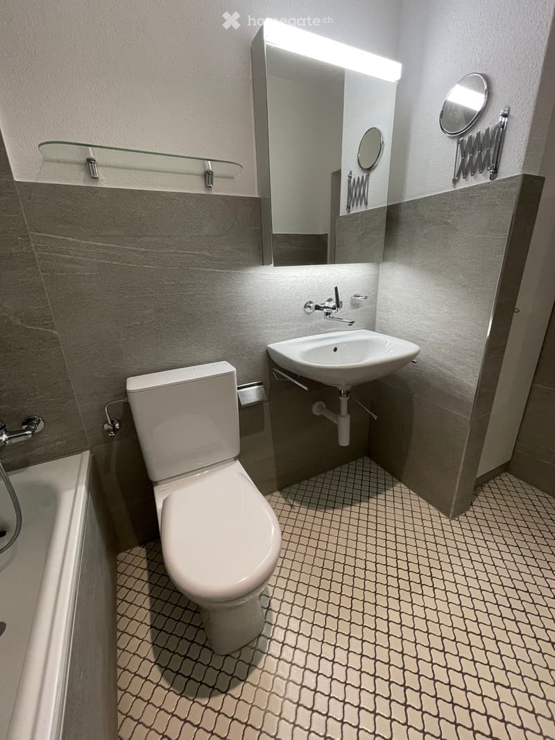 Bathroom with bathtub, toilet, sink, mirror, and wall-mounted shelves