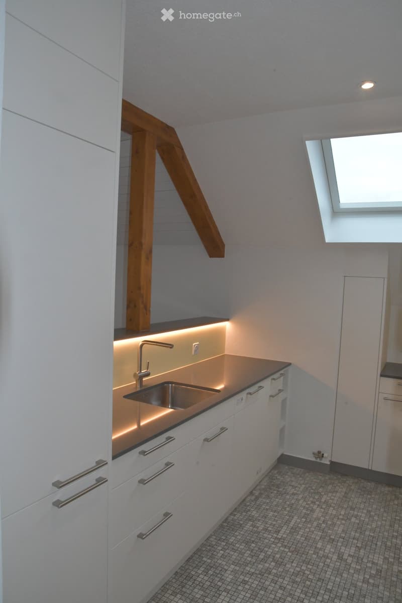 modern kitchen with white cabinets, granite countertop, stainless steel sink, wooden beam, skylight