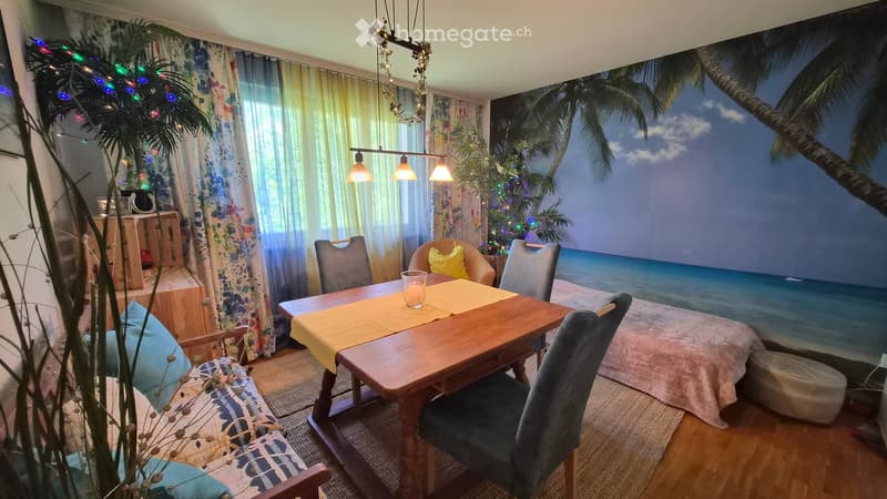 A cozy dining area with a wooden table, chairs, and a sofa, decorated with a beach-themed mural on the wall and festive Christmas lights.