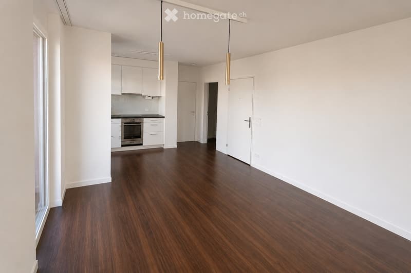 Empty room with wooden flooring, white walls, and white cabinetry in the background. No furniture or personal items are present.